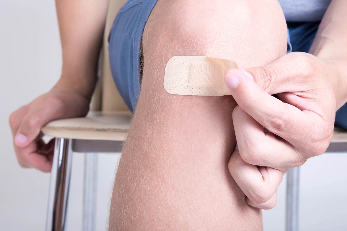 A close-up shot of a person applying a bandage to a wound, representing the application of a polymer wound dressing infused with terpenes for enhanced healing.