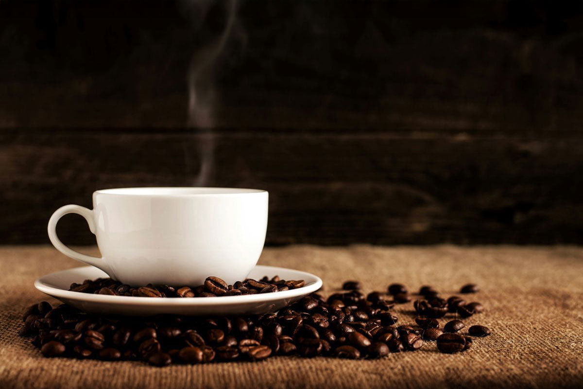 Steaming cup of coffee surrounded by fresh beans, illustrating the aromatic complexity of terpenes in coffee.