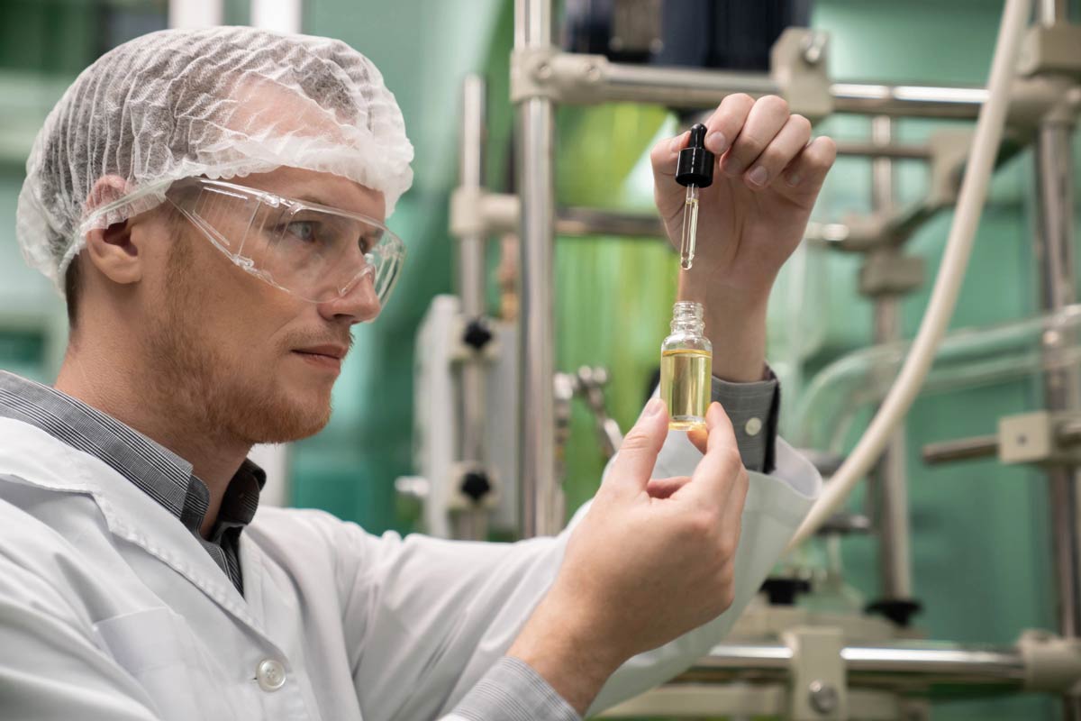 Scientist analyzing a dropper bottle of terpenes in a lab, showing how to prevent terpenes side effects through dilution.