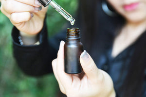 A person holds a glass bottle and a dropper with terpenes to use them as an alternative to treat cancer.